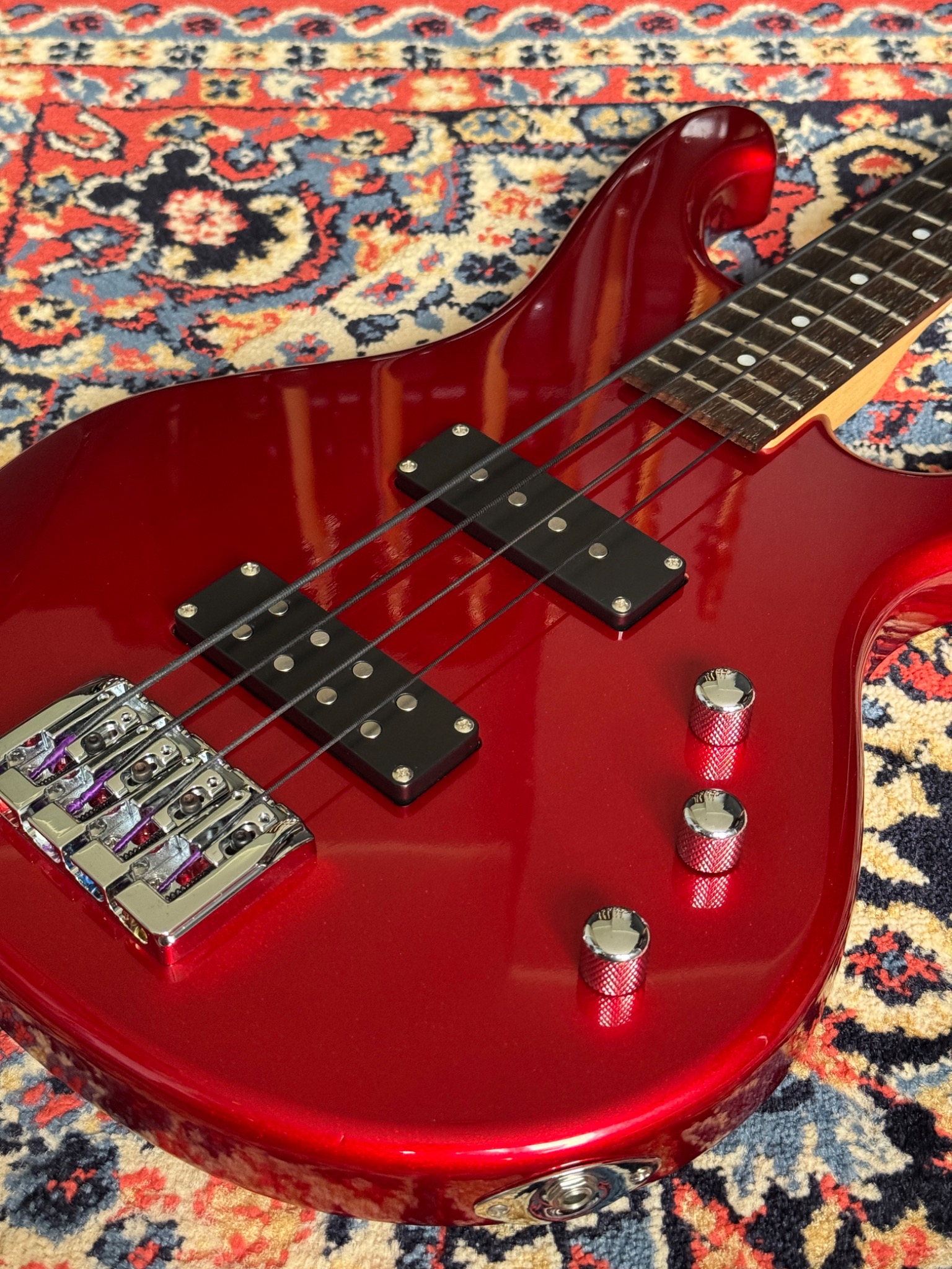 Close view of the red body, pickups, bridge and control knobs
